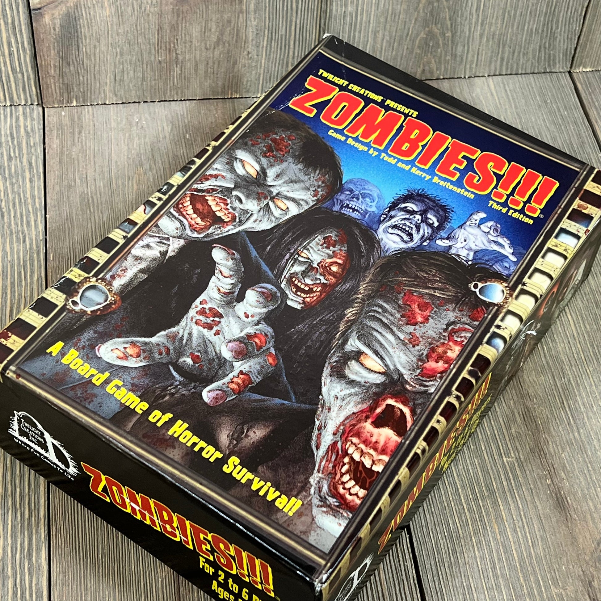 Zombie Survival Board Game box with vivid artwork, showing terrifying zombie characters, suitable for 2-6 players, ages 15+.