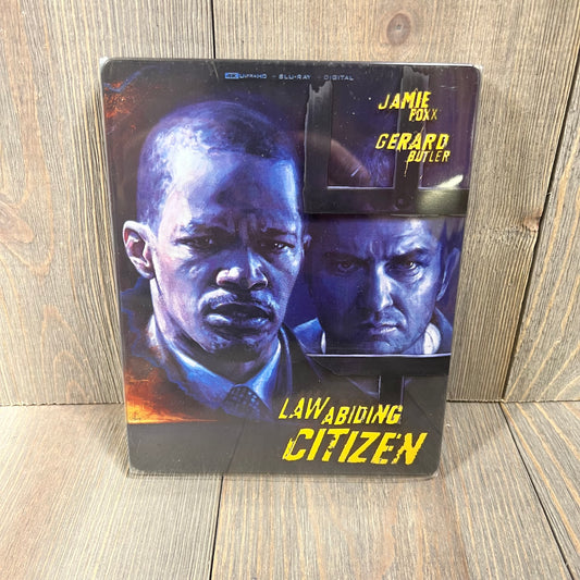 Alt text: "Law Abiding Citizen 4K UHD Blu-ray Steelbook featuring illustrated cover art of two men, Amazon Exclusive edition.