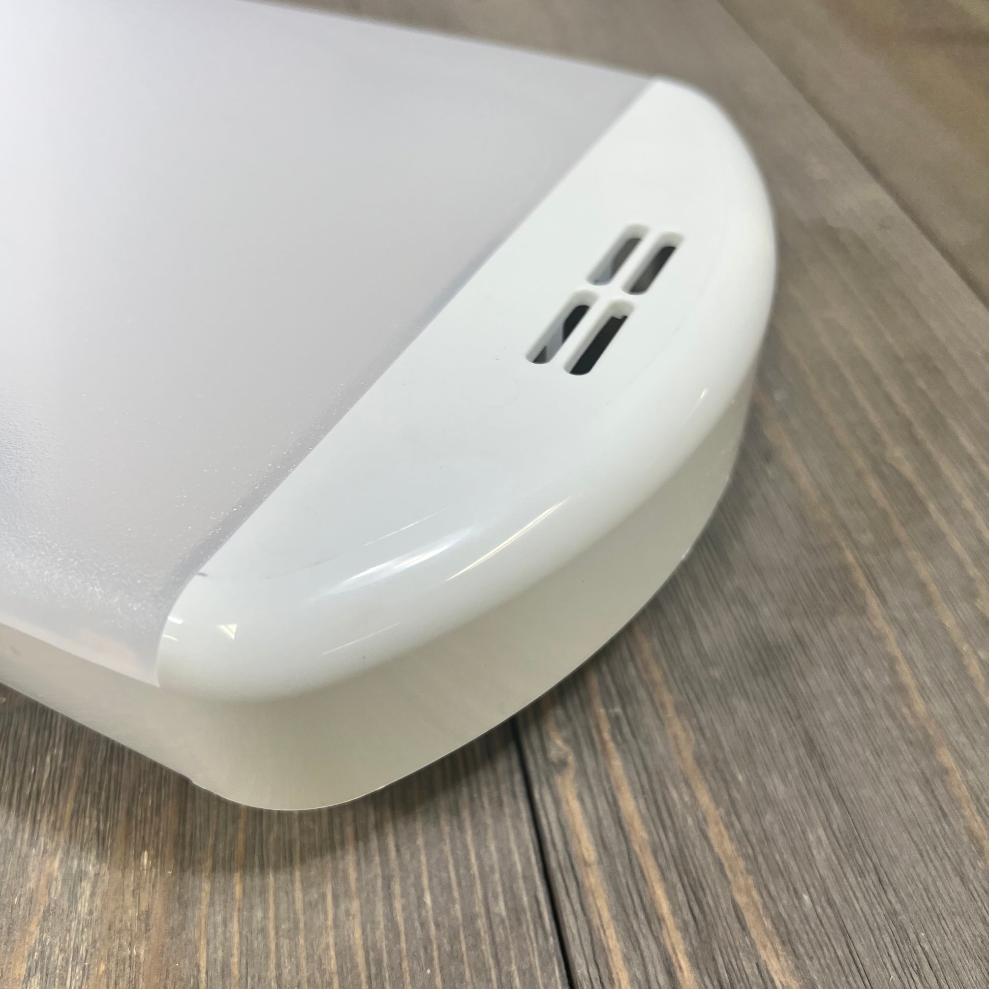 Alt text: Close-up of a white refrigerator LED light module assembly on a wooden surface.