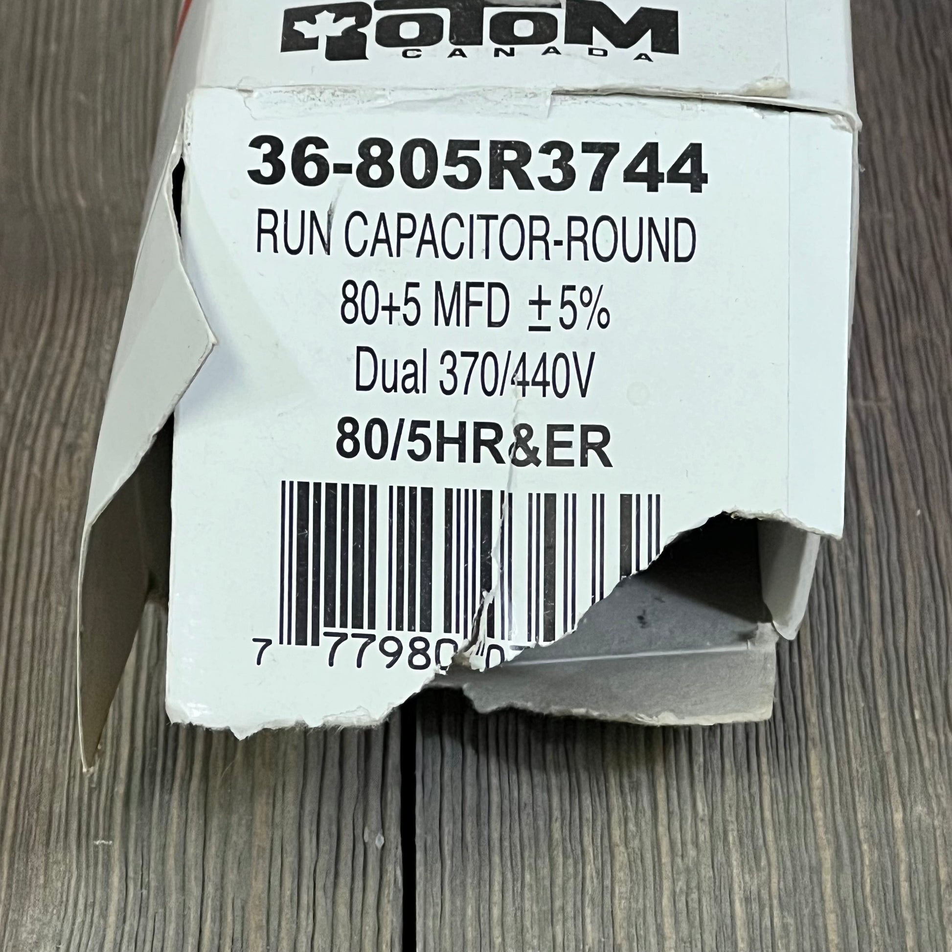 Damaged box of Rotom Start Capacitor 36-805R3744, featuring specs 80+5 MFD, dual voltage 370/440V, barcode visible.