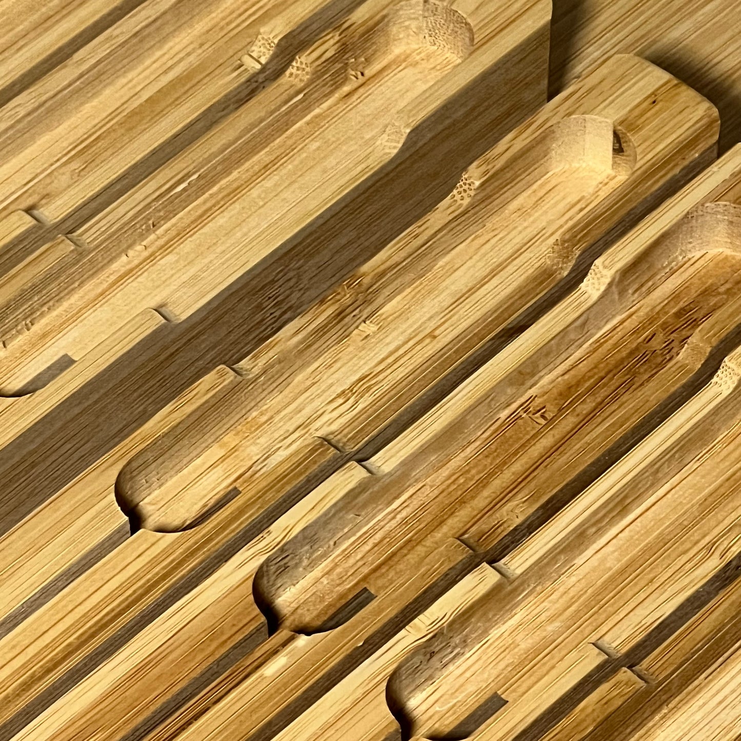 Bamboo in-drawer knife block organizer with slots for 16 knives and a sharpener, showcasing smooth, natural wood finish.