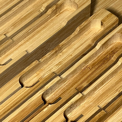 Bamboo in-drawer knife block organizer with slots for 16 knives and a sharpener, showcasing smooth, natural wood finish.