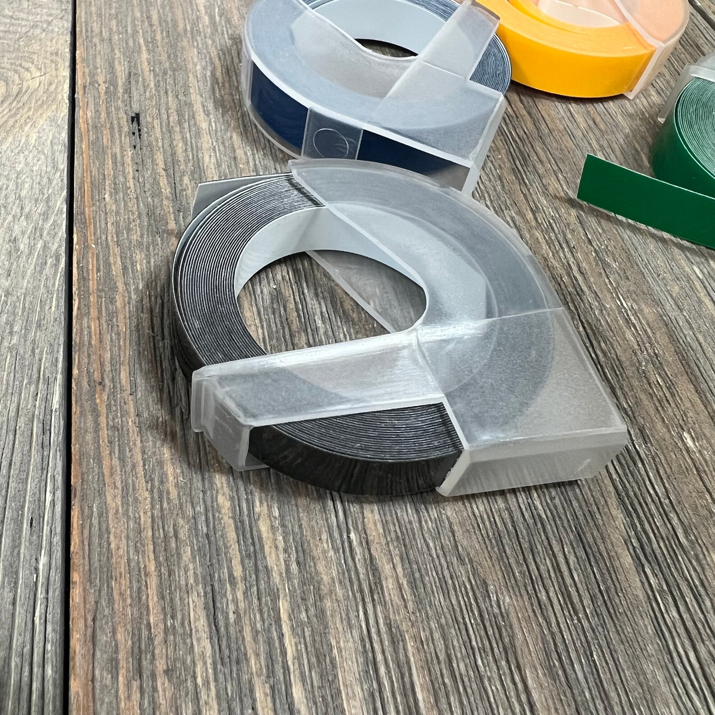 Alt text: Embossing label tape rolls for Dymo label makers on a wooden surface.