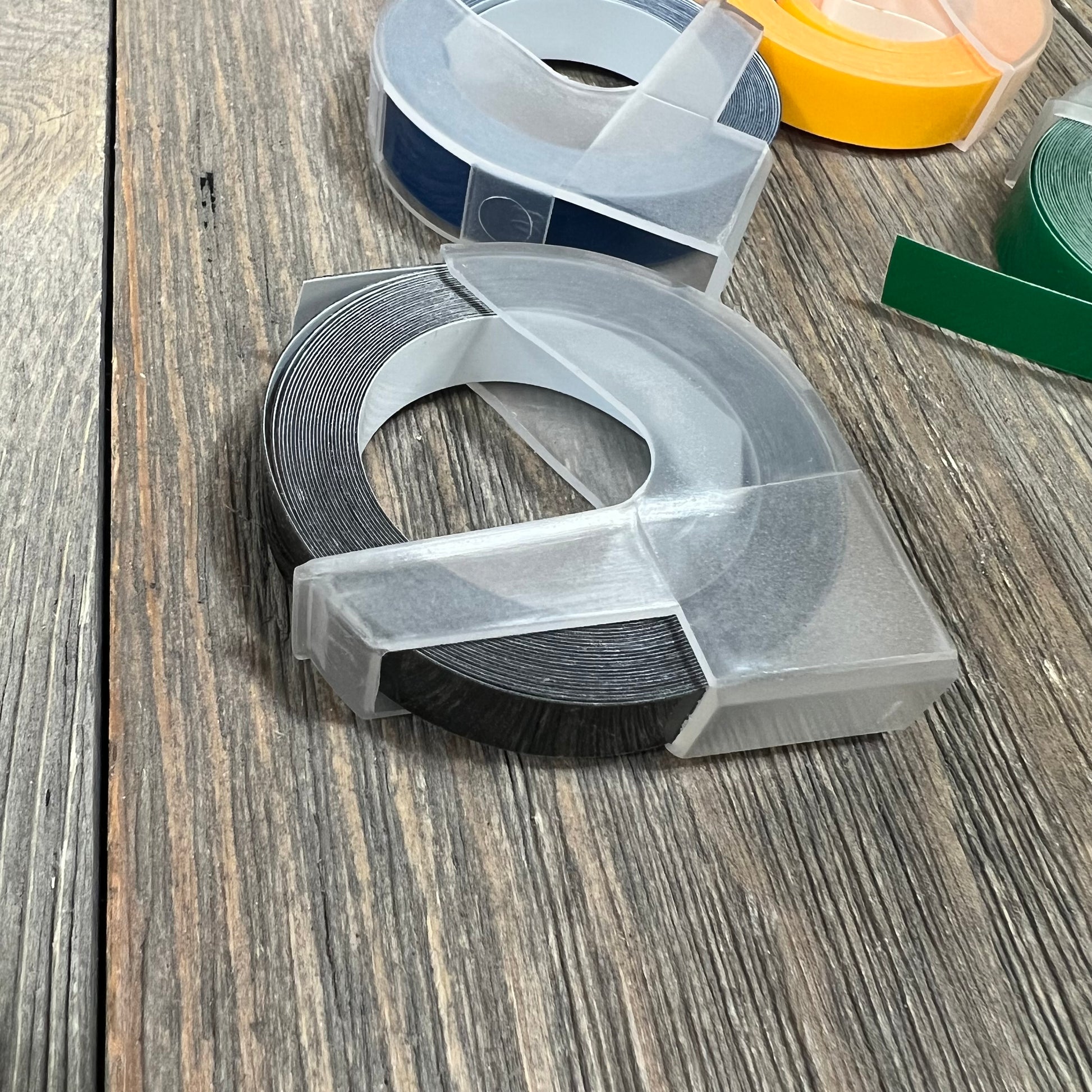 Alt text: Embossing label tape rolls for Dymo label makers on a wooden surface.