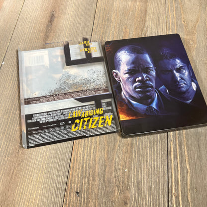 Alt text: "Law Abiding Citizen 4K UHD + Blu-ray + Digital Steelbook set on a wooden surface."