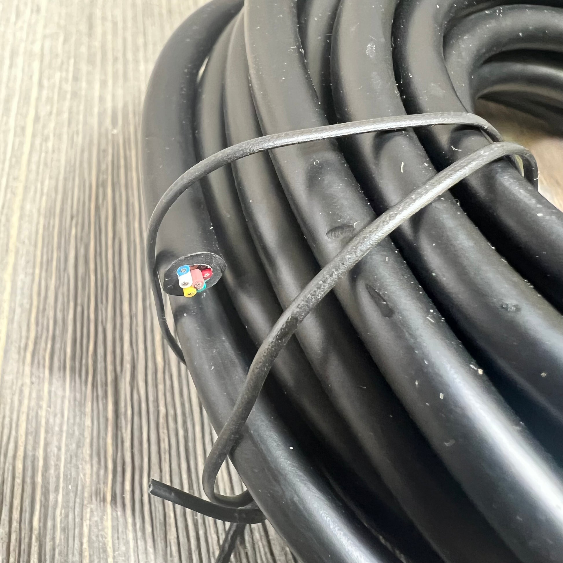 Alt text: Coiled black replacement cable for SuperFlo and WhisperFlo pumps on a wooden surface.