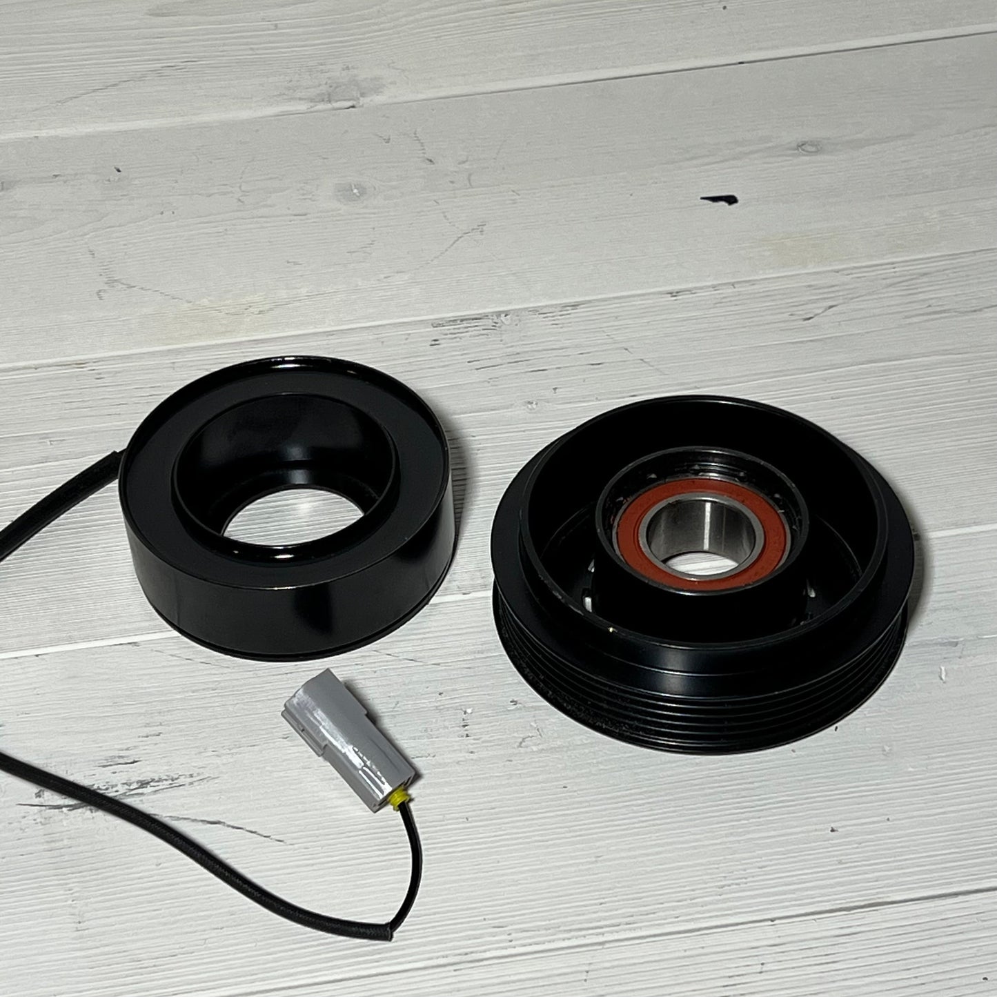 AC Compressor Clutch Set for Mazda 3 2010-2013 with repair components on a wooden surface.