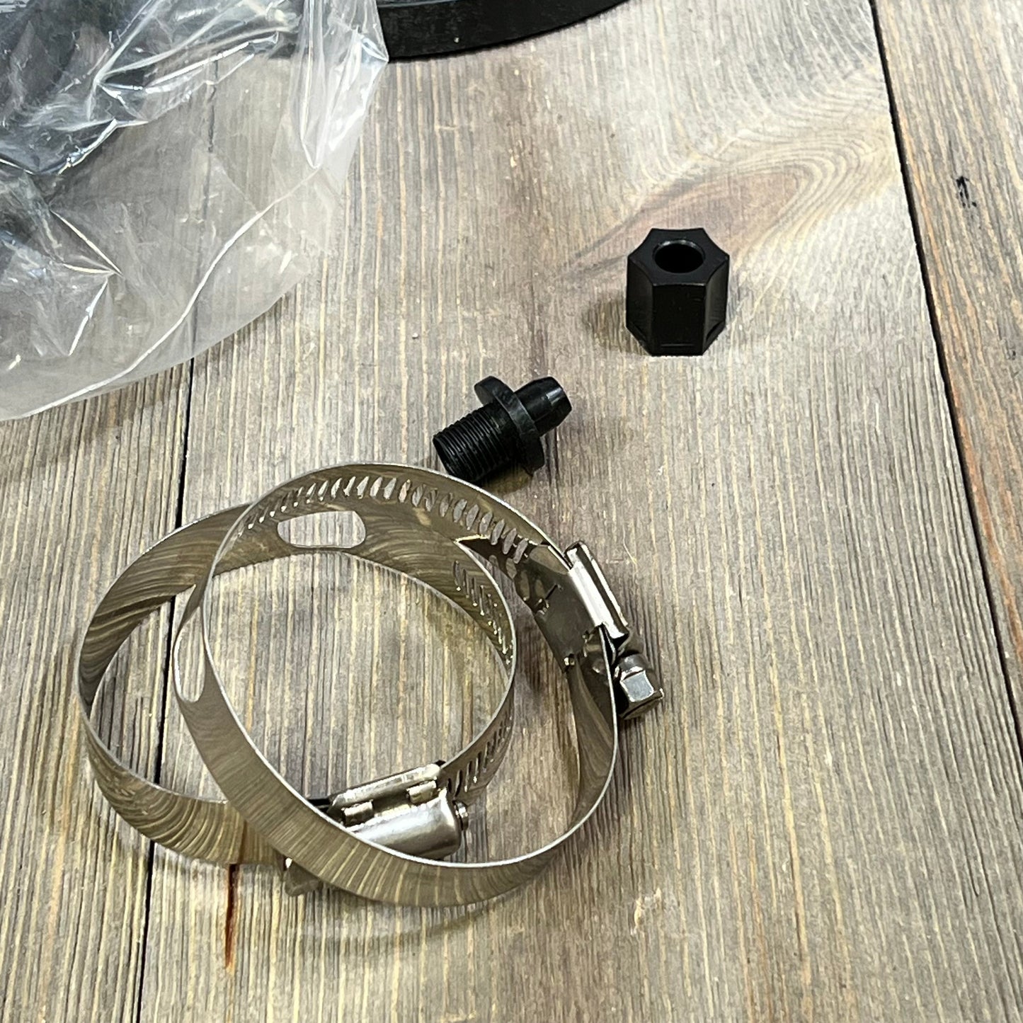 Accessories for the 1046017433-CL220 automatic chlorinator feeder, including clamps and connectors, on a wooden surface.