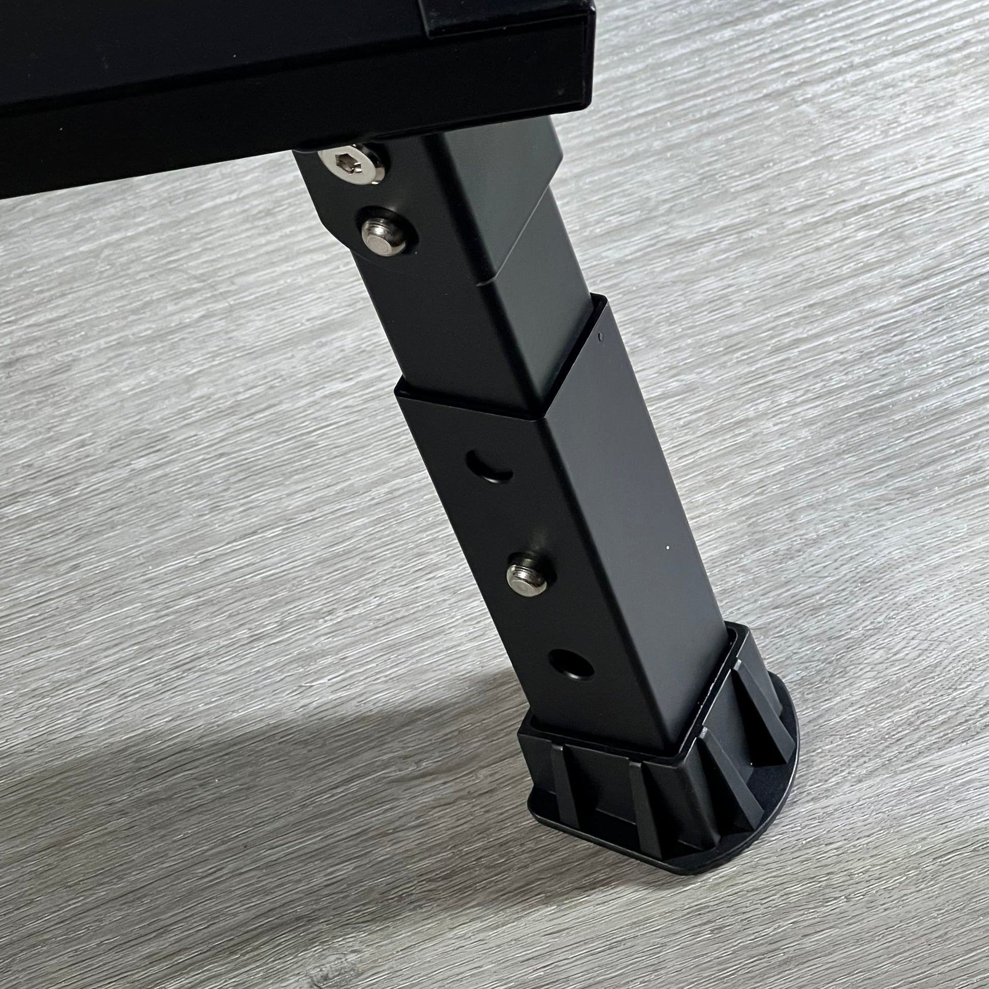 Adjustable black aluminum leg of DEPSUNNY RV step with non-slip rubber foot on wooden floor.
