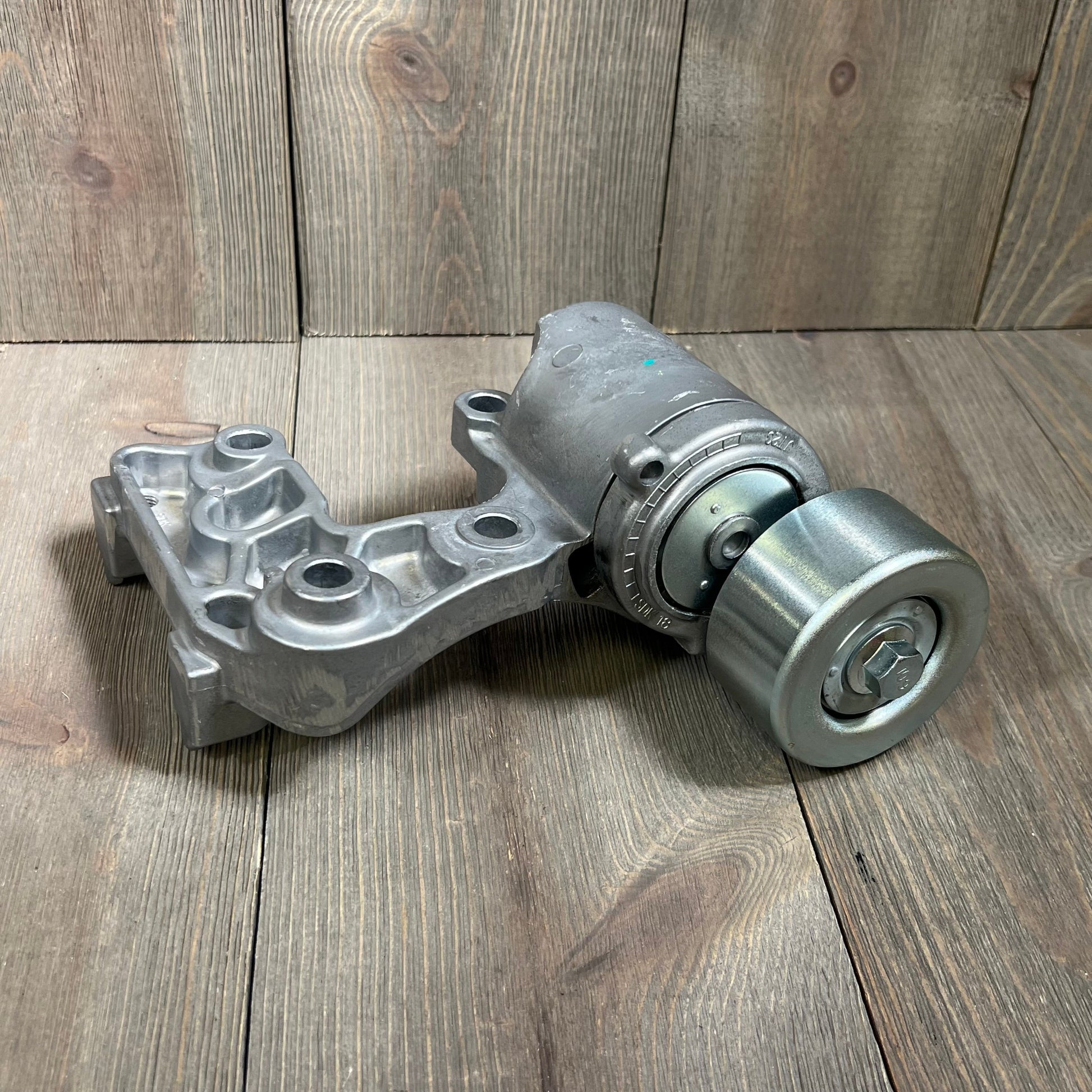 Toyota Lexus drive belt tensioner assembly for 3.5L 4.0L V6 engines, part number 16620-31040, on wooden surface.