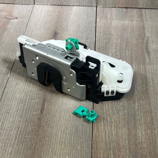 Rear passenger side door lock actuator latch for Ford F150 2009-14, with green clips, on wooden surface.
