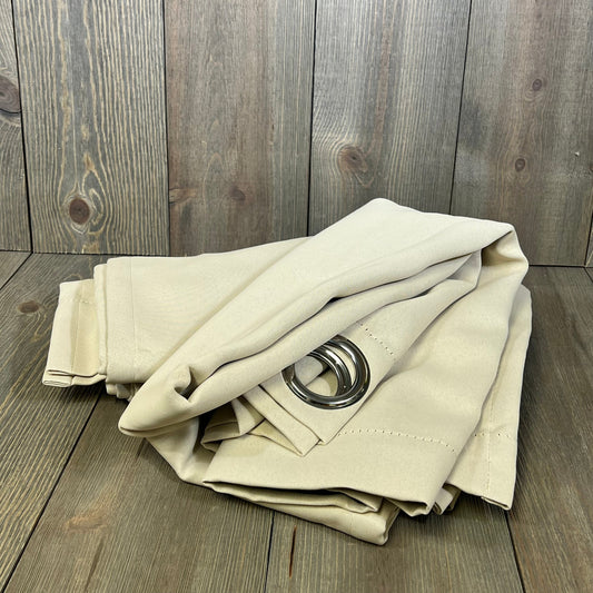 Champagne blackout curtains with grommets, folded, showcasing thermal insulation and light-blocking fabric on wooden background.