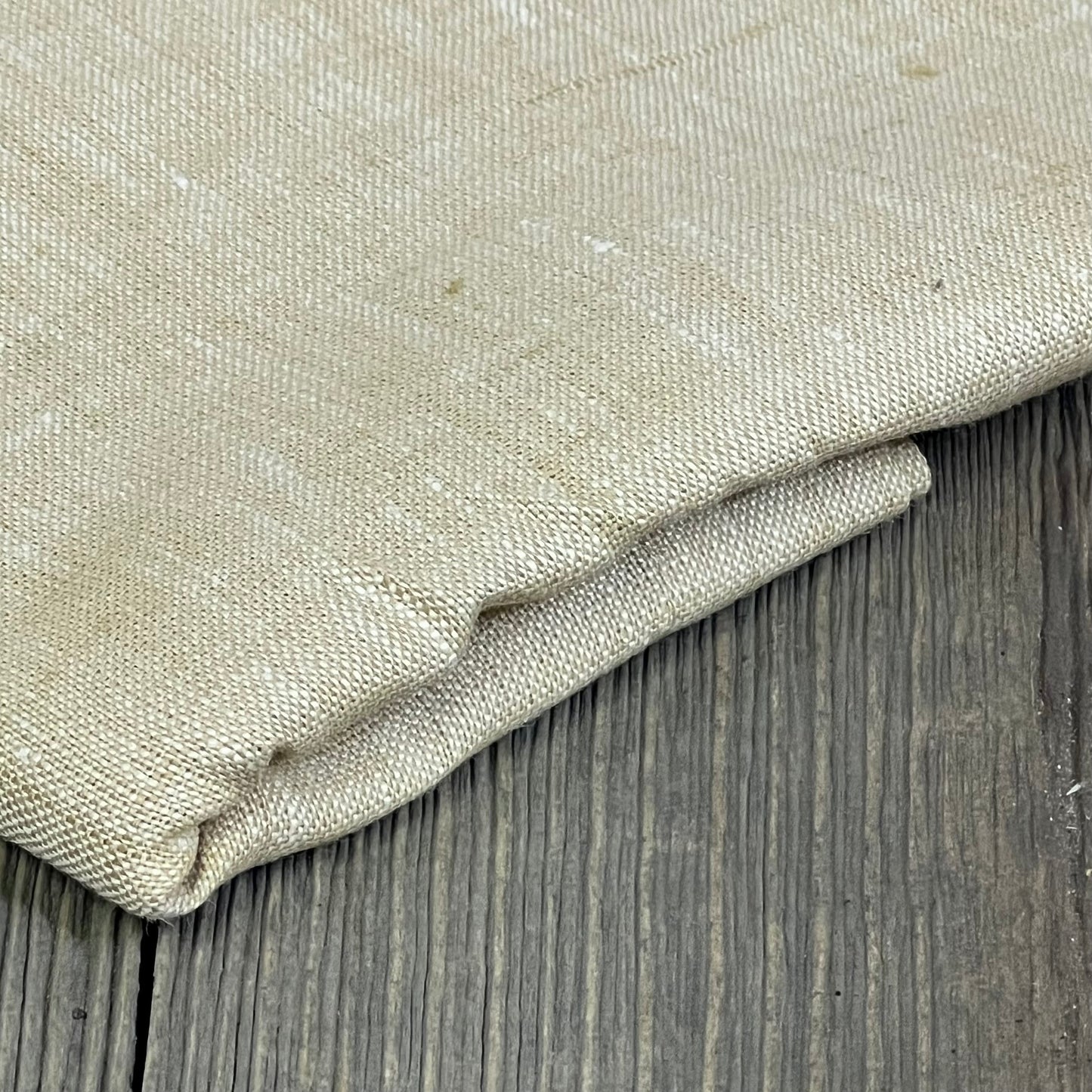 Champagne beige linen table runner folded on wooden surface, showcasing texture and quality for elegant home decor.