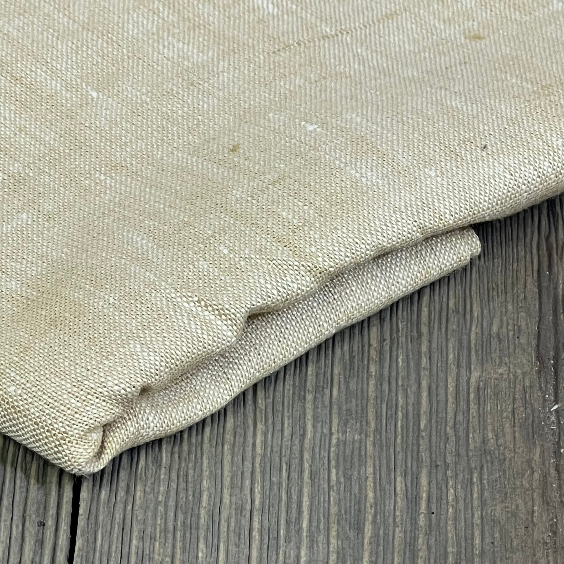 Champagne beige linen table runner folded on wooden surface, showcasing texture and quality for elegant home decor.