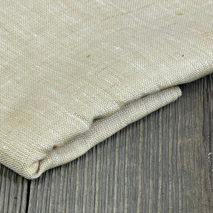 Champagne beige linen table runner folded on wooden surface, showcasing texture and quality for elegant home decor.