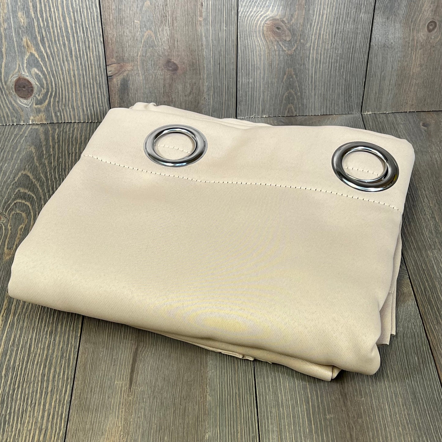 Beige ChrisDowa blackout curtains with grommets, folded on a wooden surface, 63-inch length, thermal insulated.