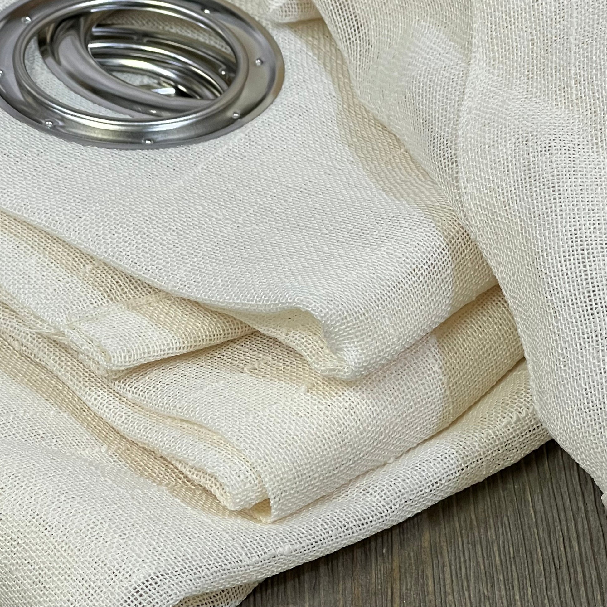 Ivory sheer curtain panel with grommet top, perfect for outdoor patio or pergola, showcasing weatherproof fabric detail.