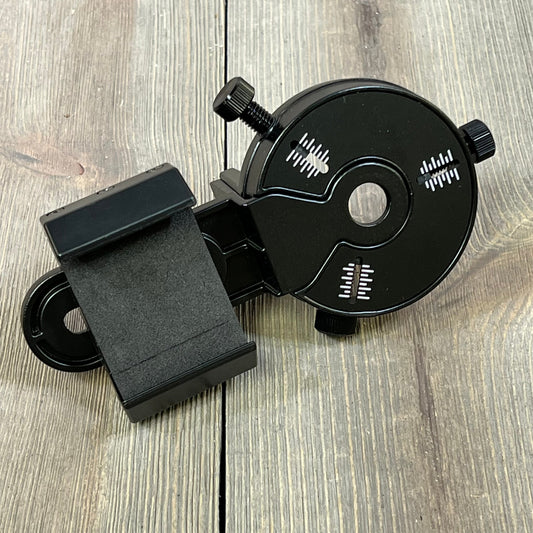 Black smartphone scope adapter with adjustable knobs, designed for spotting scopes, binoculars, and telescopes on wood surface.