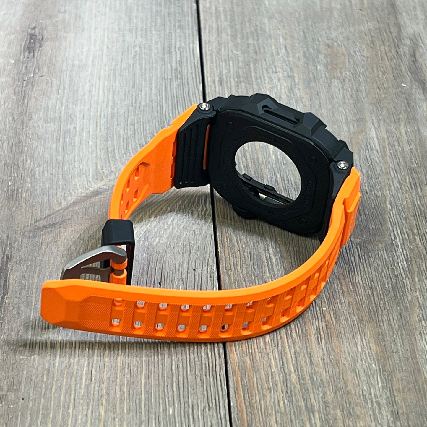 Orange rugged case with tactical band for Apple Watch 46mm, showcasing military-grade shockproof bumper design on wood surface.