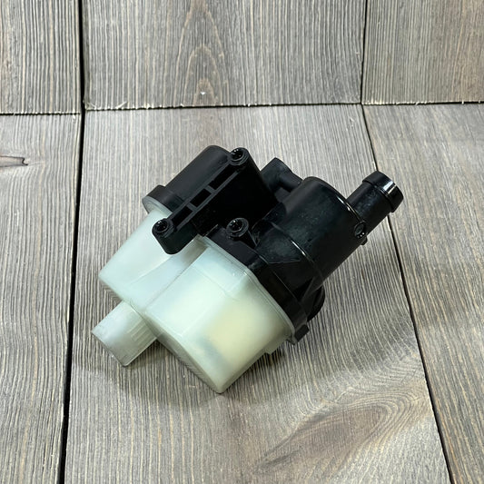 Fuel vapor leak detection pump for BMW models, featuring durable black plastic design on wooden background.