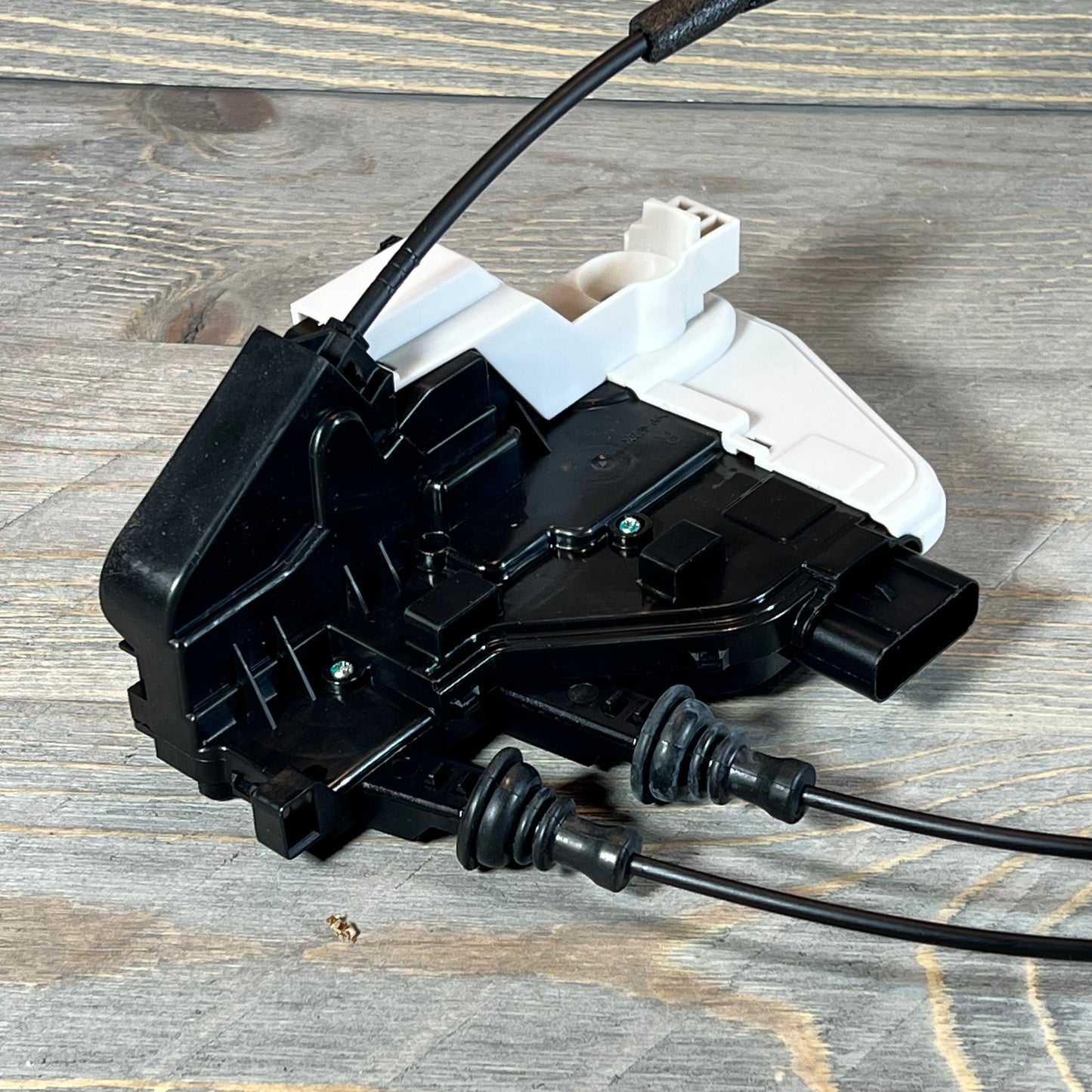 Black and white Power Door Lock Actuator for Hyundai Santa Fe, Front Right Passenger Side, on a wooden surface.