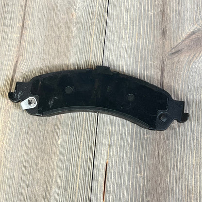 Rear ceramic brake pad from ECCPP, designed for Cadillac, Chevrolet, GMC. Durable and quiet performance on wooden surface.