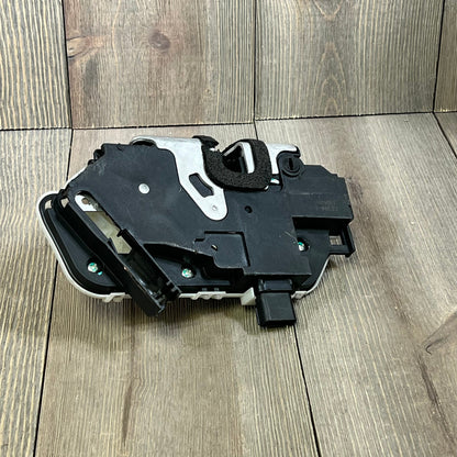 REVOTUNE rear left door latch lock actuator for Ford F-150 and Lincoln, black and silver components on wood surface.