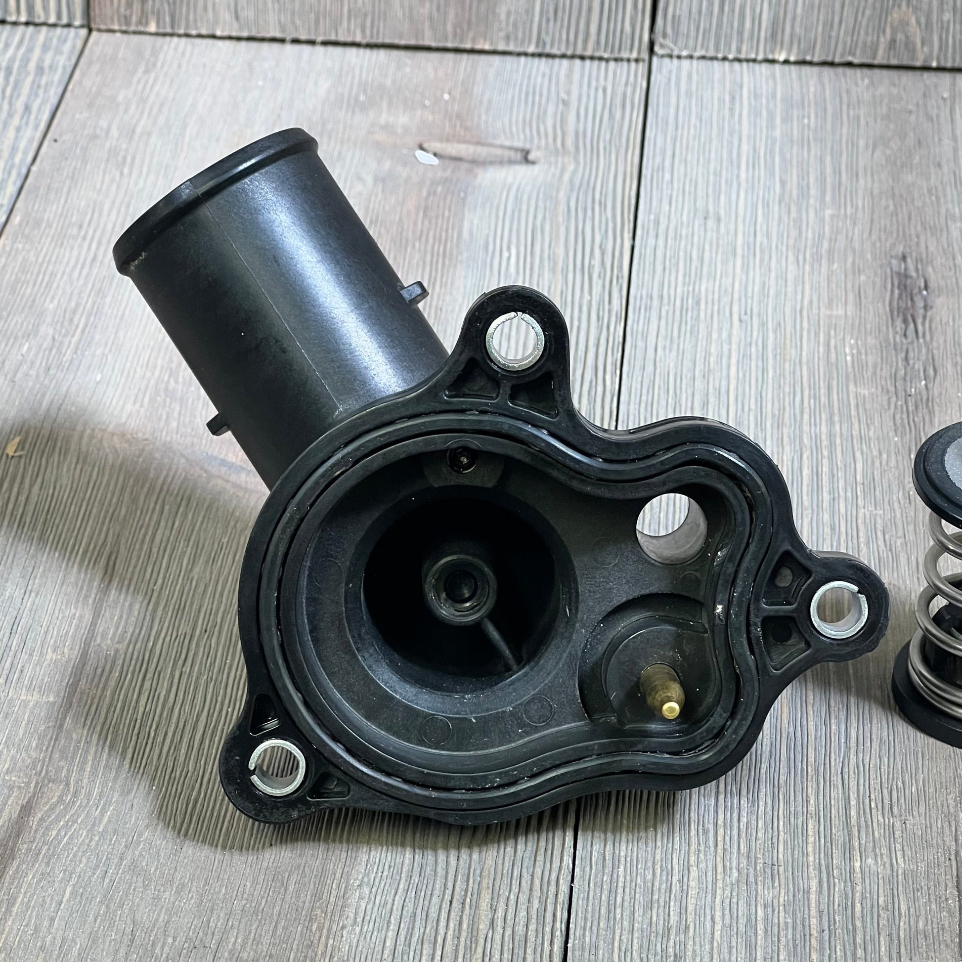 Thermostat housing assembly for Dodge Jeep Ram 3.6L V6, compatible with 2016-2022 models, detailed view on wood surface.