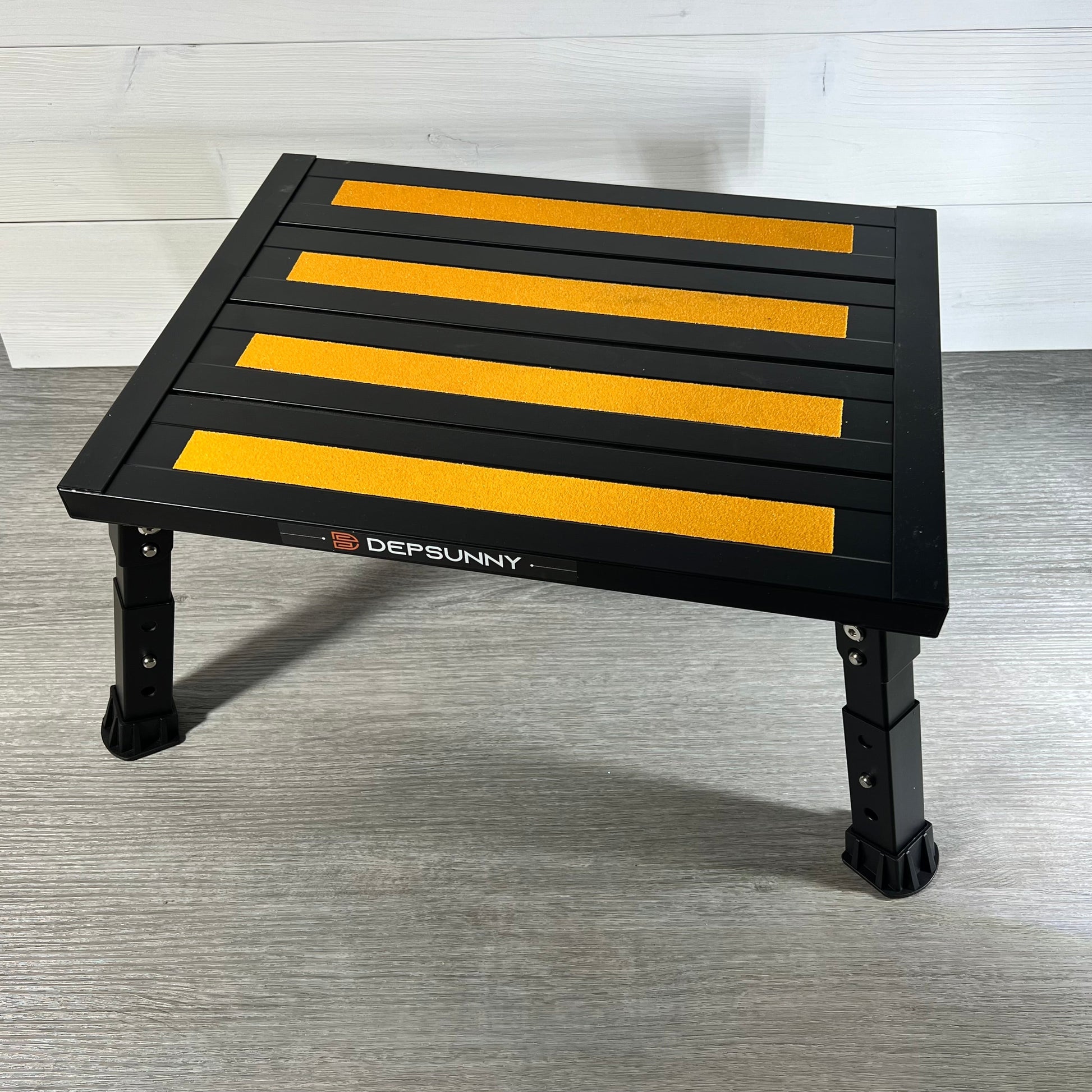 Black DEPSUNNY RV step stool with adjustable height, non-slip yellow strips, and rubber feet on a wooden floor.