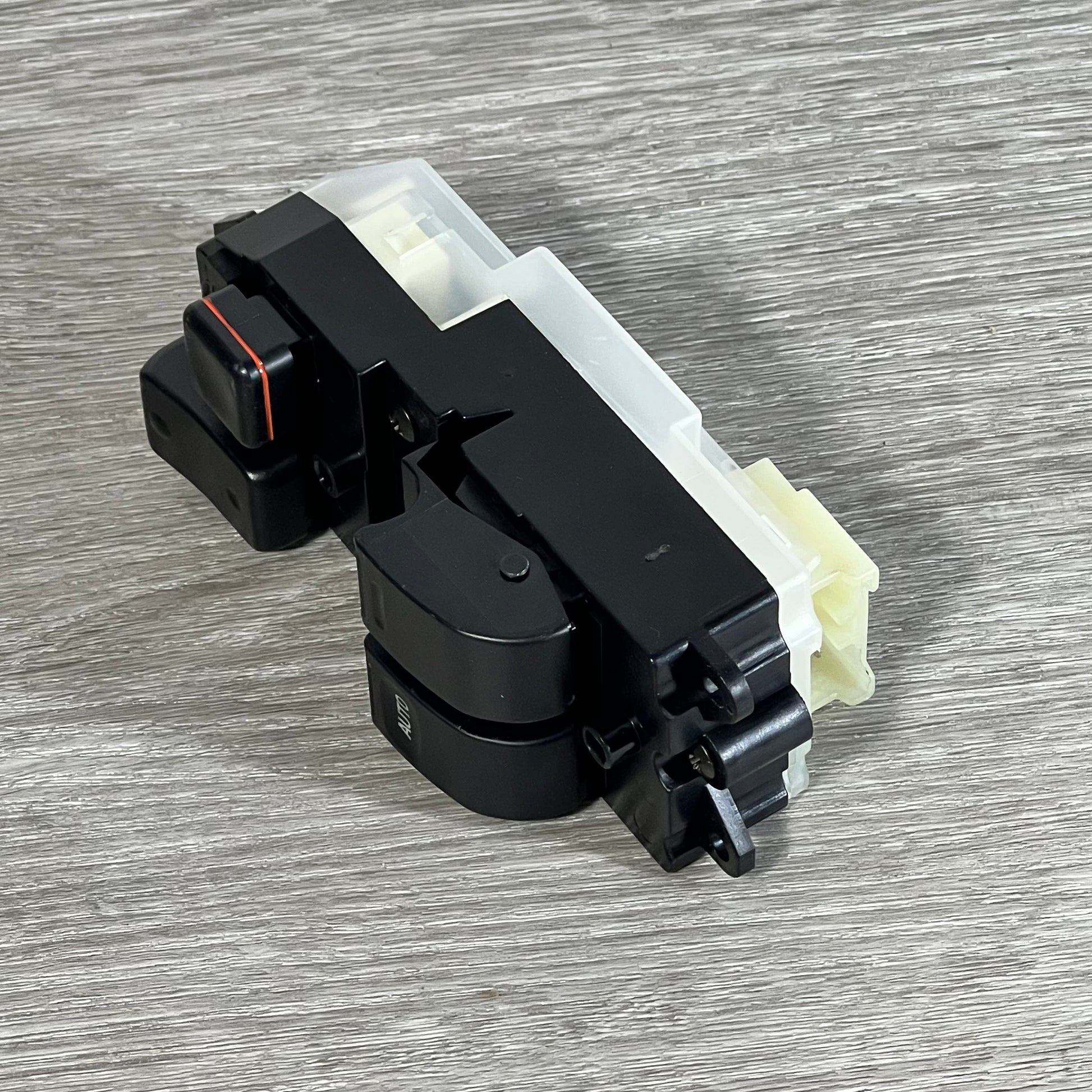 Black Dorman 901-711 driver side window switch for Toyota, shown on a wooden surface, angled view.