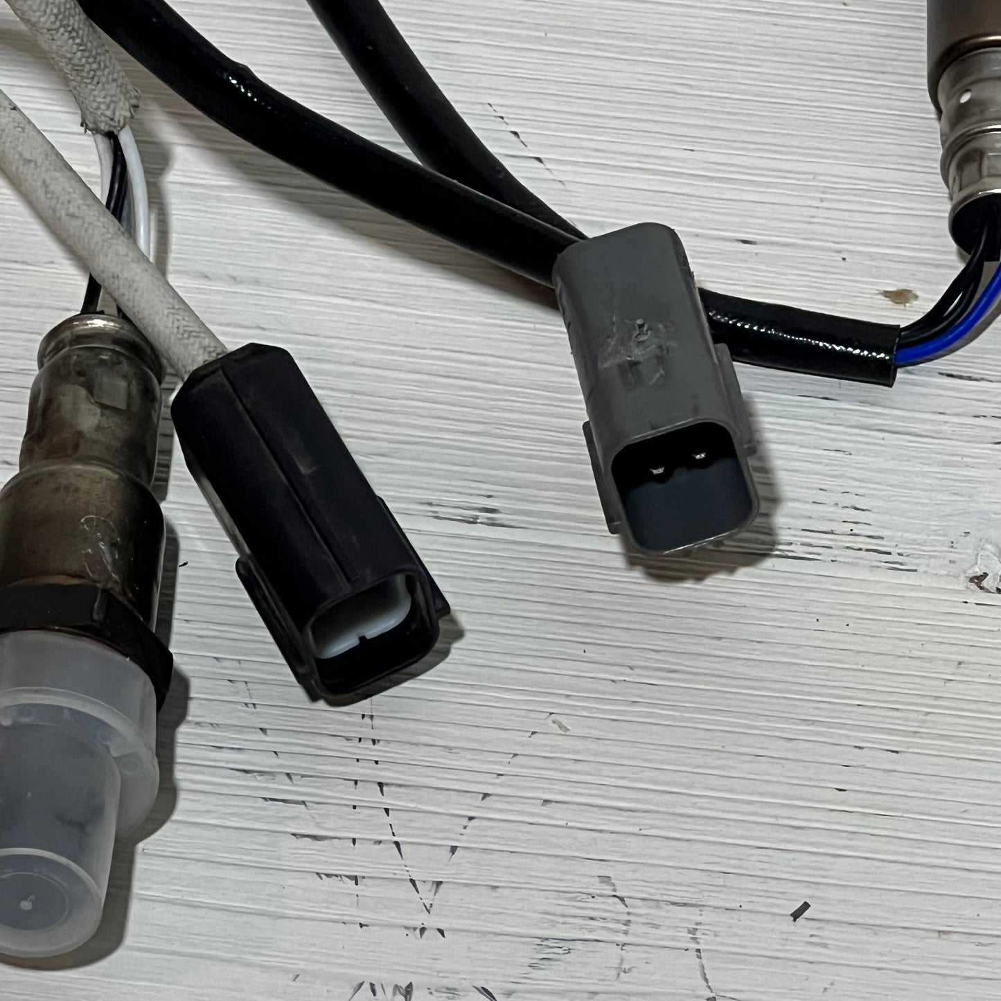 Close-up of Nissan Rogue 2.5L upstream and downstream oxygen sensor connectors on a white background.