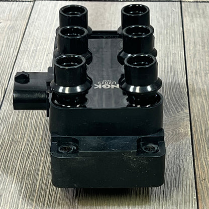 NGK U2029 (48806) ignition coil for distributorless systems, showcasing six high-quality terminals on a wooden surface.