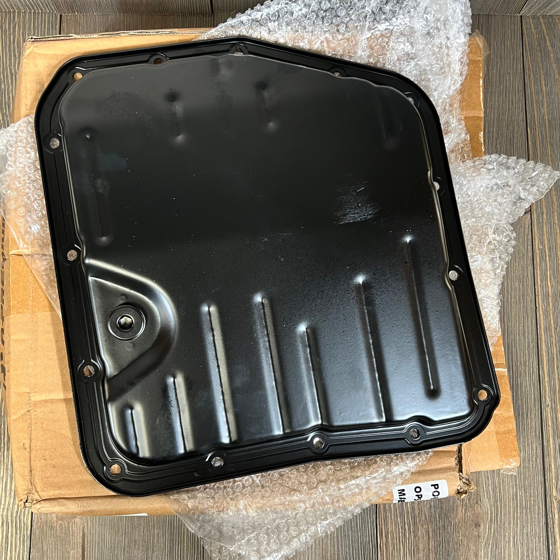 Premium black transmission oil pan with drain plug for Toyota Camry and Corolla, featuring durable 15 bolt holes.