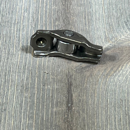Ford 3L3Z-6564-BA rocker arm valve assembly on wooden surface, showcasing sturdy metal construction.