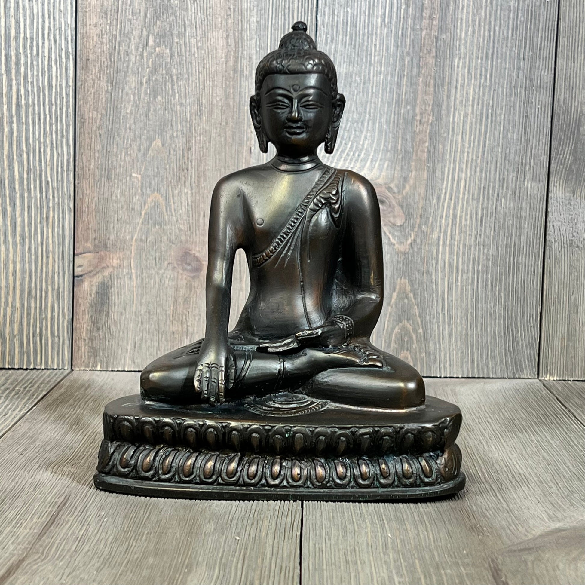 Seated bronze Buddha statue on a detailed pedestal, capturing serene meditation and spiritual harmony.