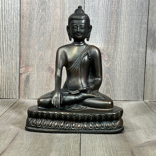 Seated bronze Buddha statue on a detailed pedestal, capturing serene meditation and spiritual harmony.