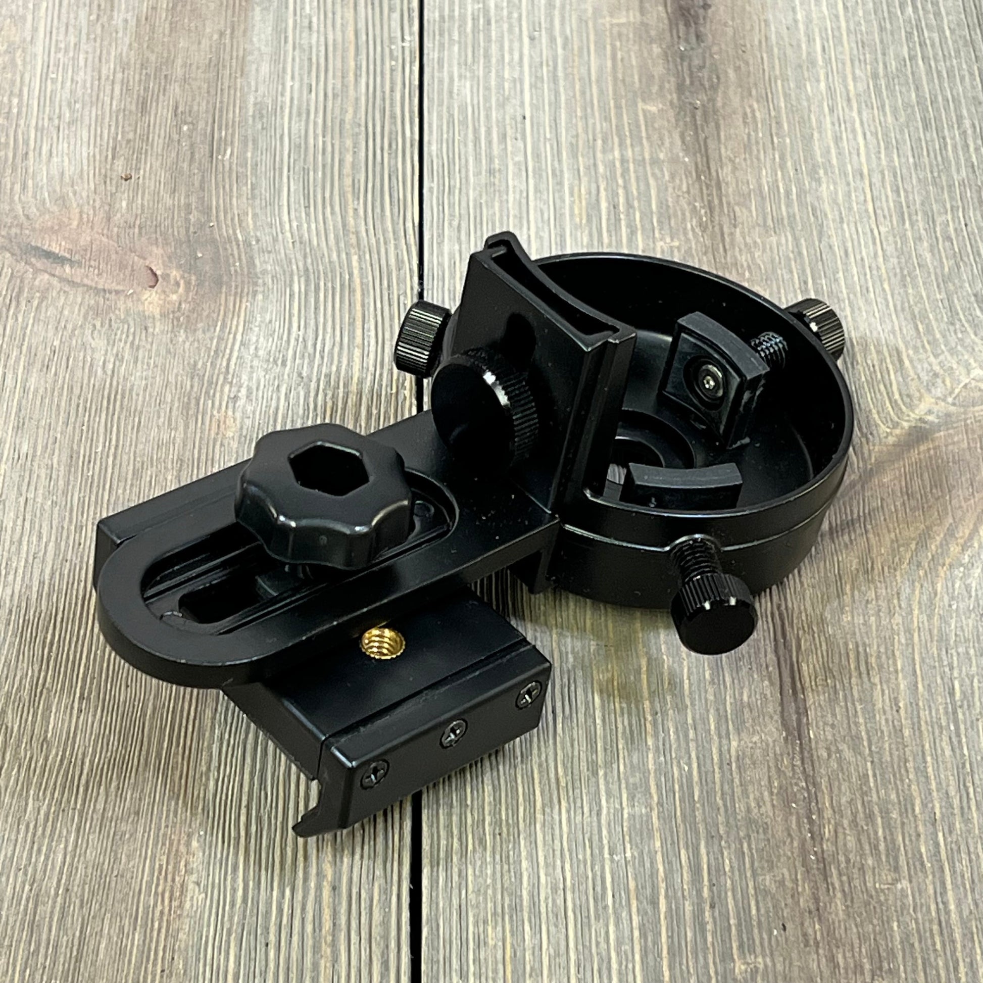 Black Celticbird smartphone scope adapter with adjustable knobs for telescopes, microscopes, and binoculars on wooden surface.