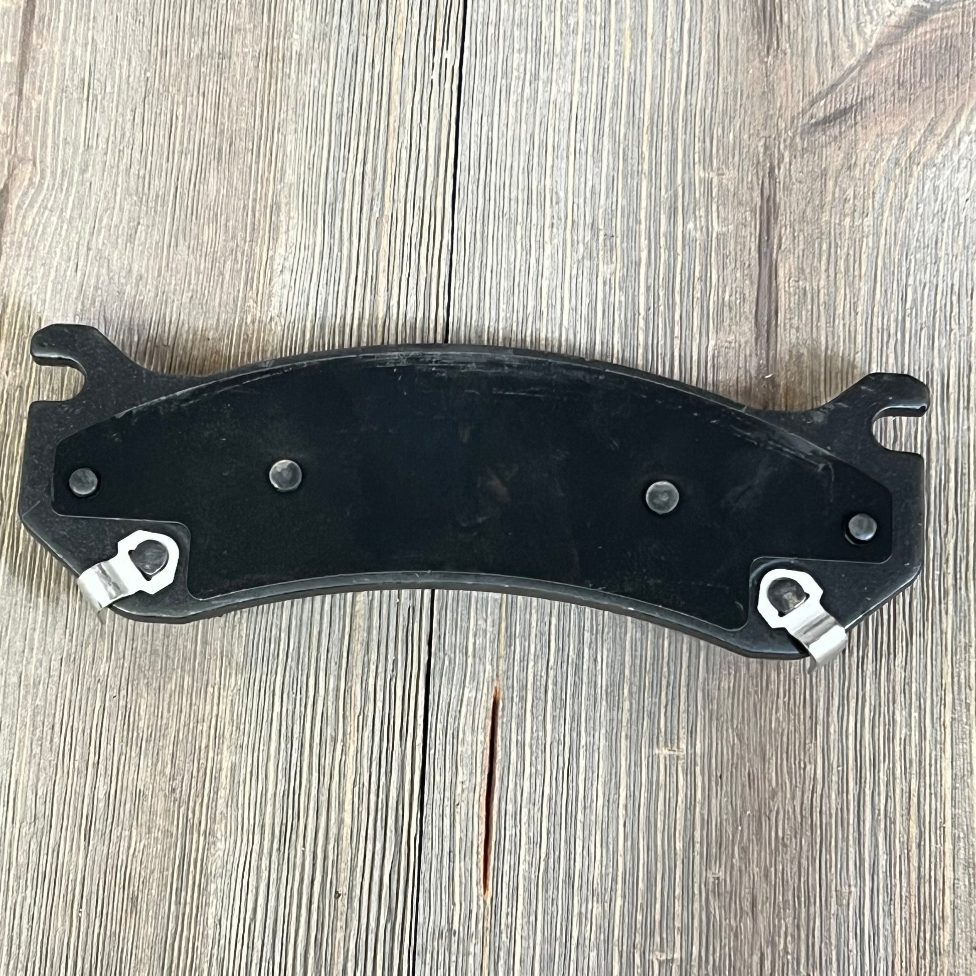 Ceramic rear brake pad for Chevrolet Suburban 2500, enhancing performance and durability on wooden background.