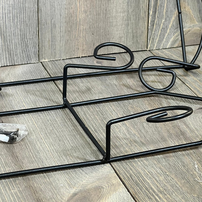 Black metal wall plate holder with three tiers, ideal for displaying dishes or decorative plates. Includes mounting hardware.
