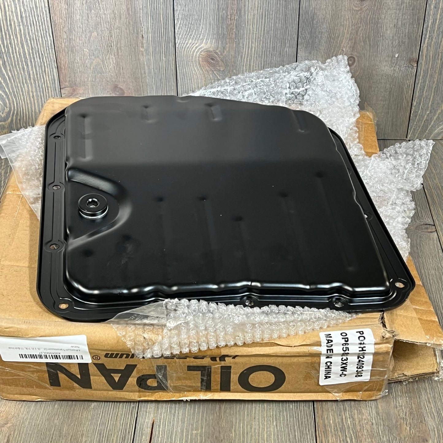 Premium transmission oil pan with drain plug for Toyota Camry, displayed on packaging, showing 15 bolt holes.