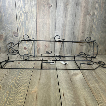 Black 3-tier vertical wall plate holder with scroll design, perfect for displaying decorative dishes on wooden background.