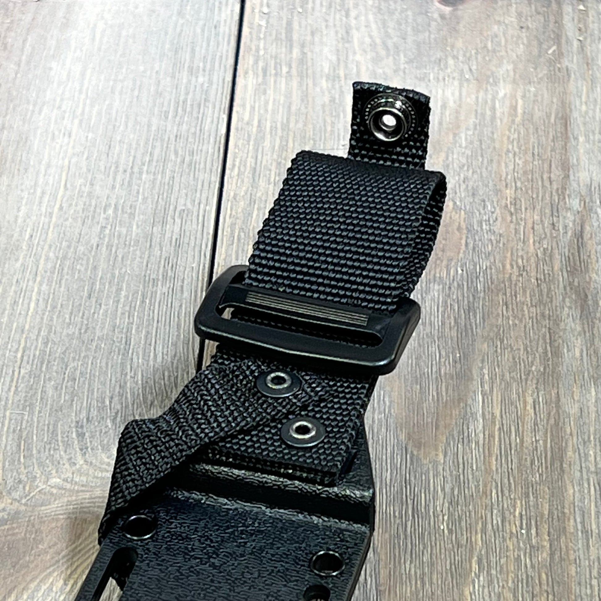 Black Kydex sheath for short Ka-Bar knife with durable strap and secure snap closure on a wooden surface.