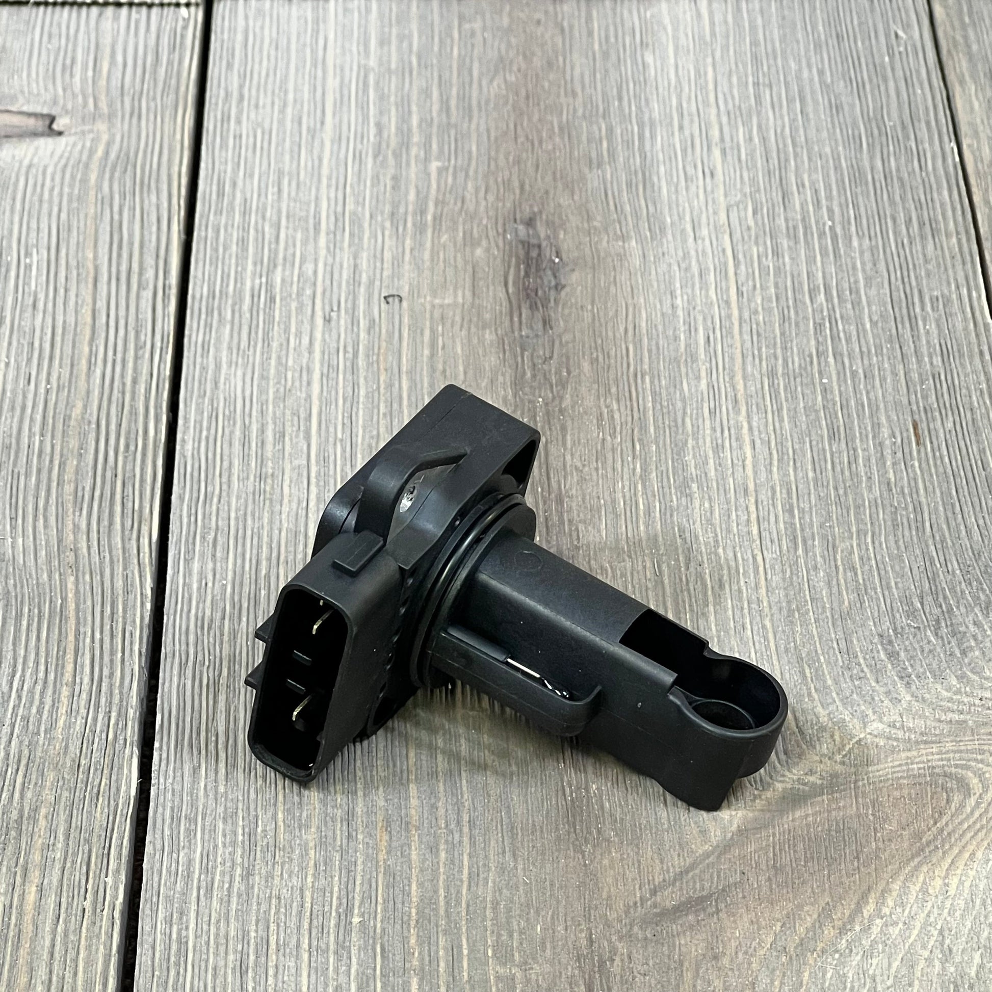 Black OYEAUTO Mass Air Flow Sensor for Toyota and Lexus, compatible with various models, shown on a wooden surface.