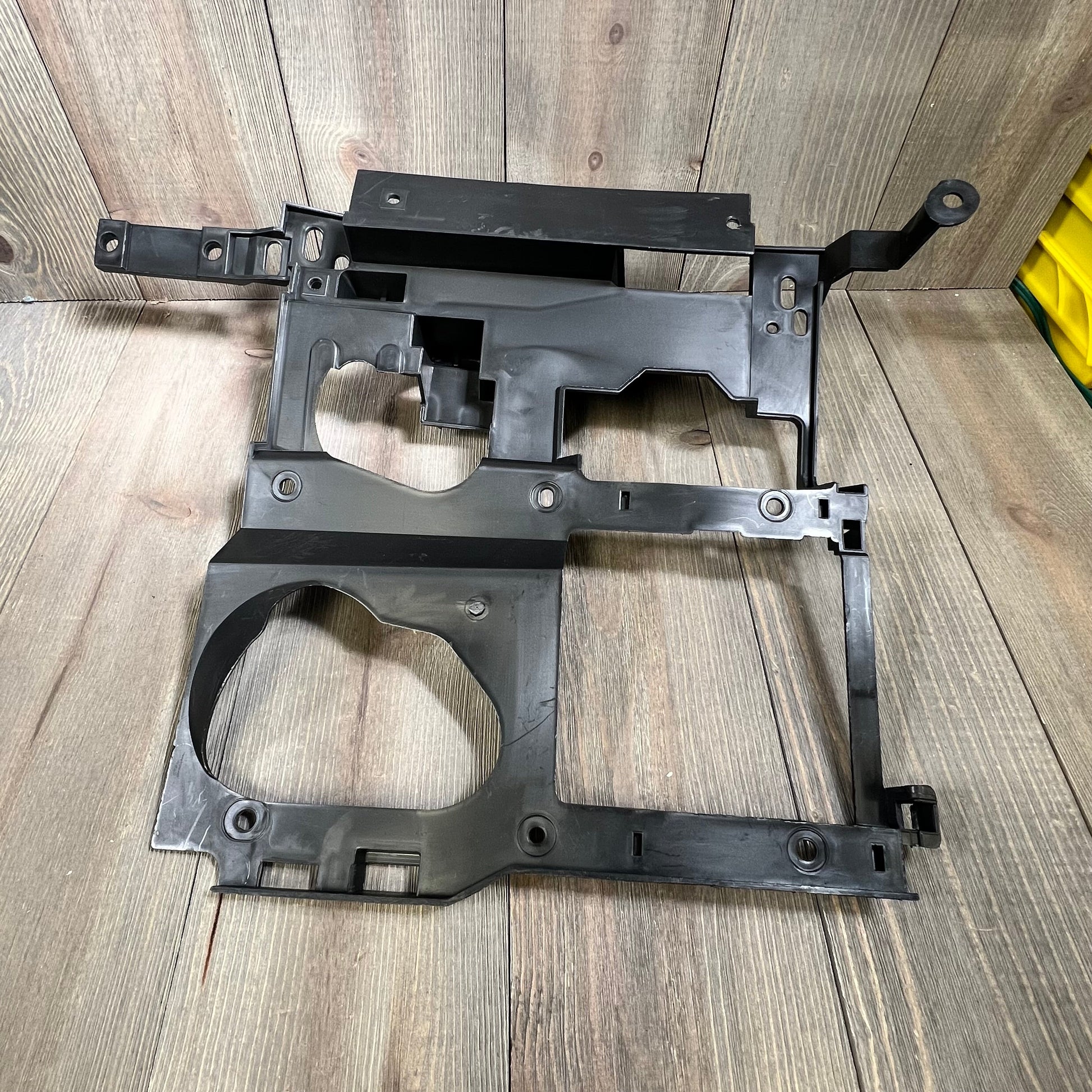 Black headlight bracket mounting panel for 1999-2006 Chevy Silverado, Suburban, Tahoe, GMC Sierra, Yukon driver and passenger sides.