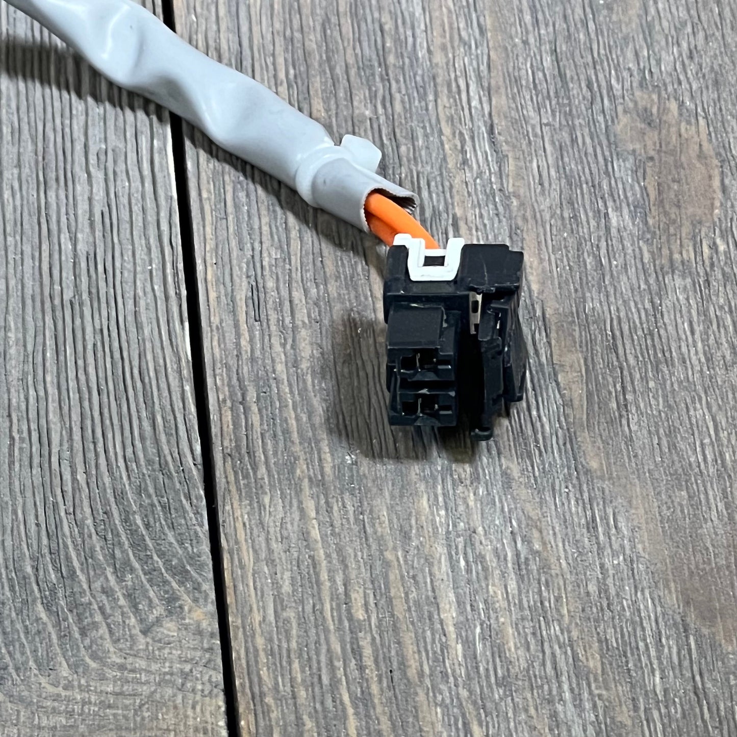 Close-up of the connector and wiring for the Yendse WH23X28418 Hotpoint GE washer drain pump motor on a wooden surface.