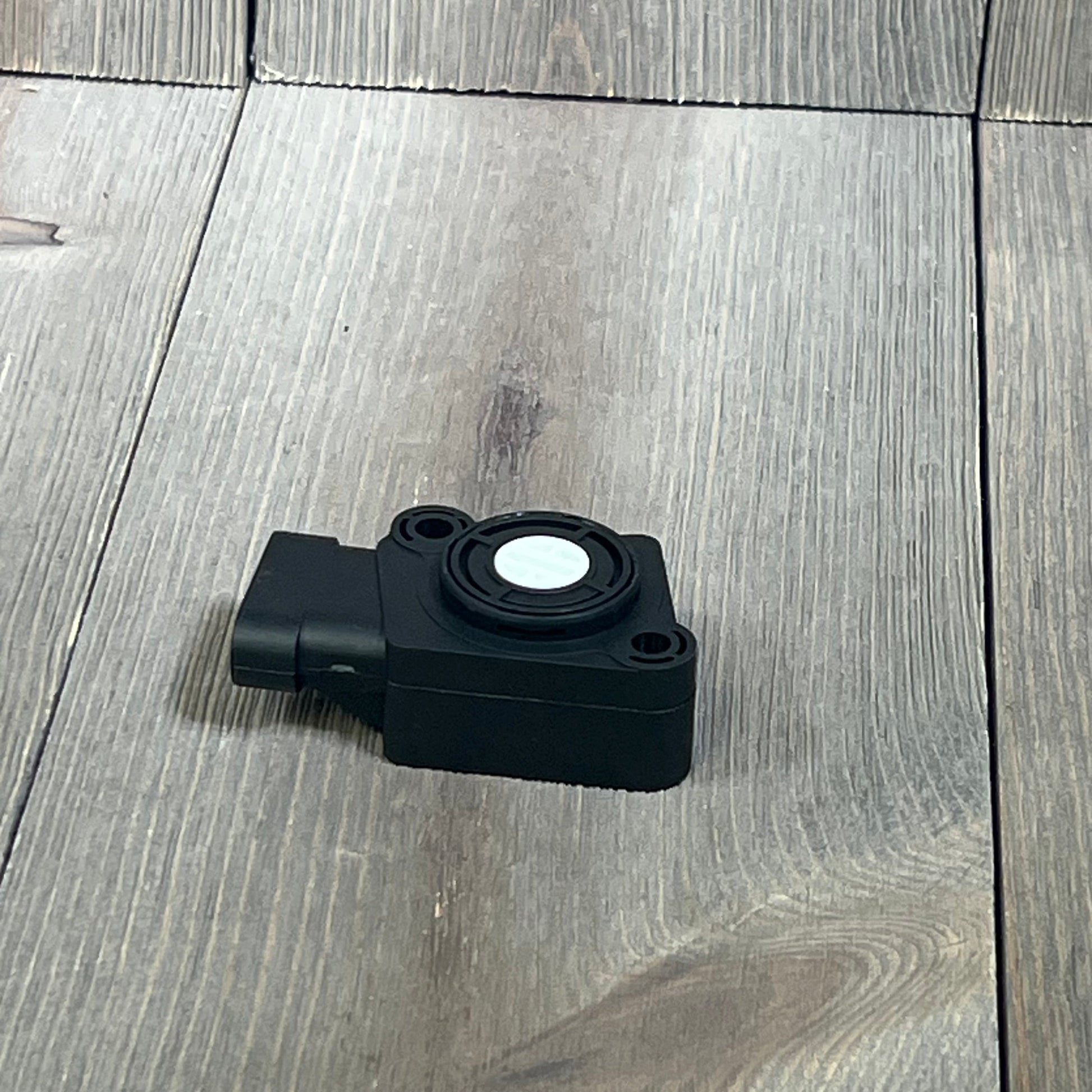 Black TPS Throttle Position Sensor Kit for Ford and Volvo trucks, model 1045796680-134143, on wooden surface.