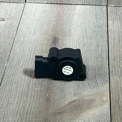 Black throttle position sensor kit for Ford, Volvo, and International Navistar trucks on wooden background.