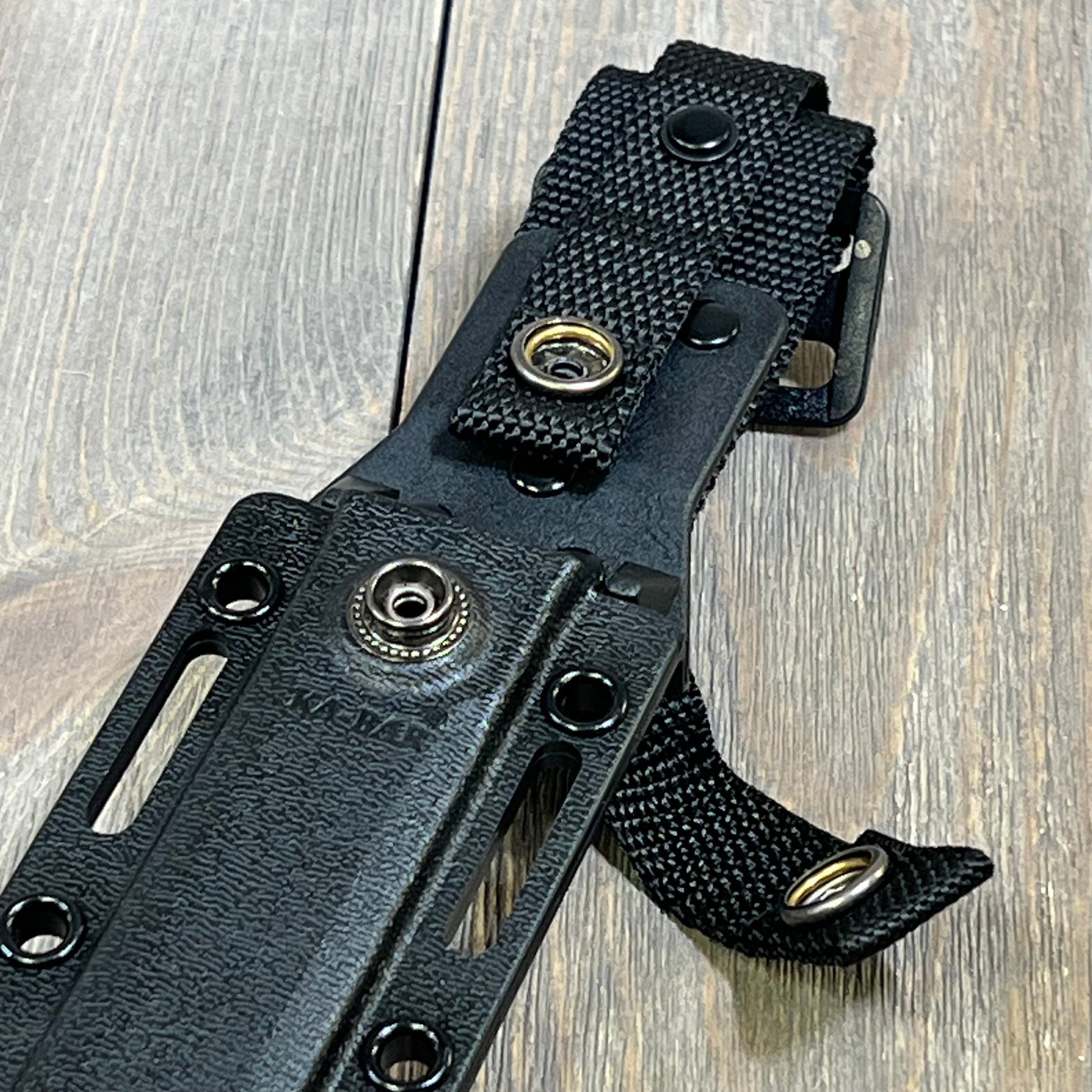 Black Ka-Bar Kydex sheath for short knives, featuring durable snap fasteners, designed for secure outdoor carry.