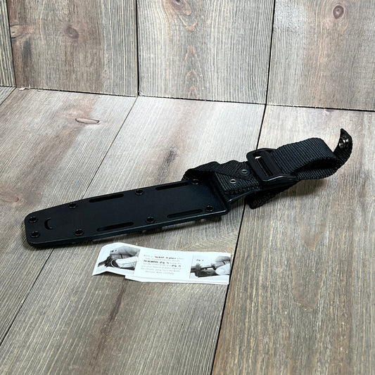 Black Ka-Bar Kydex sheath for short knives, featuring durable construction and secure strap, displayed on wooden surface.