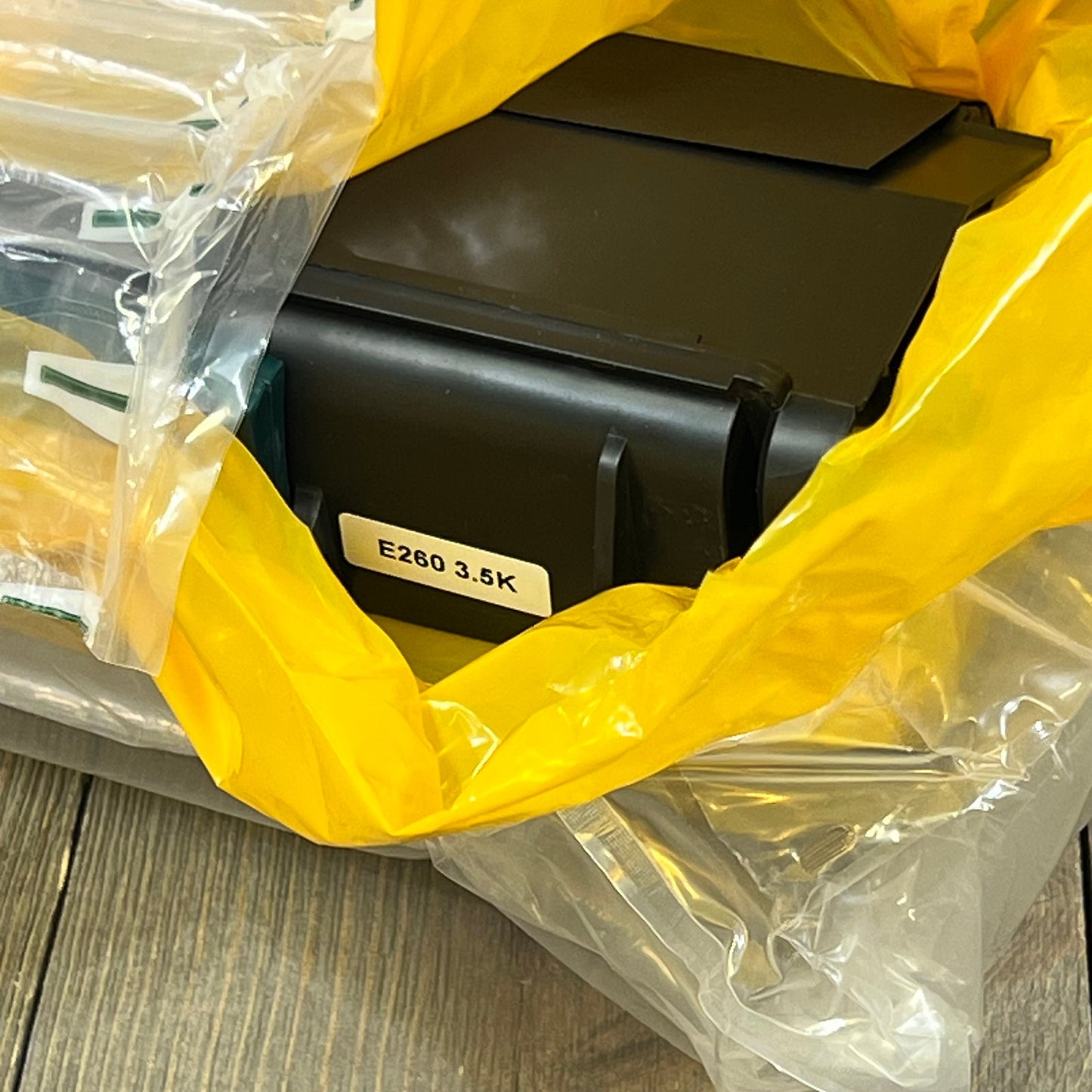 Toner cartridge replacement for Lexmark E260 series, wrapped in protective plastic, ready for installation.